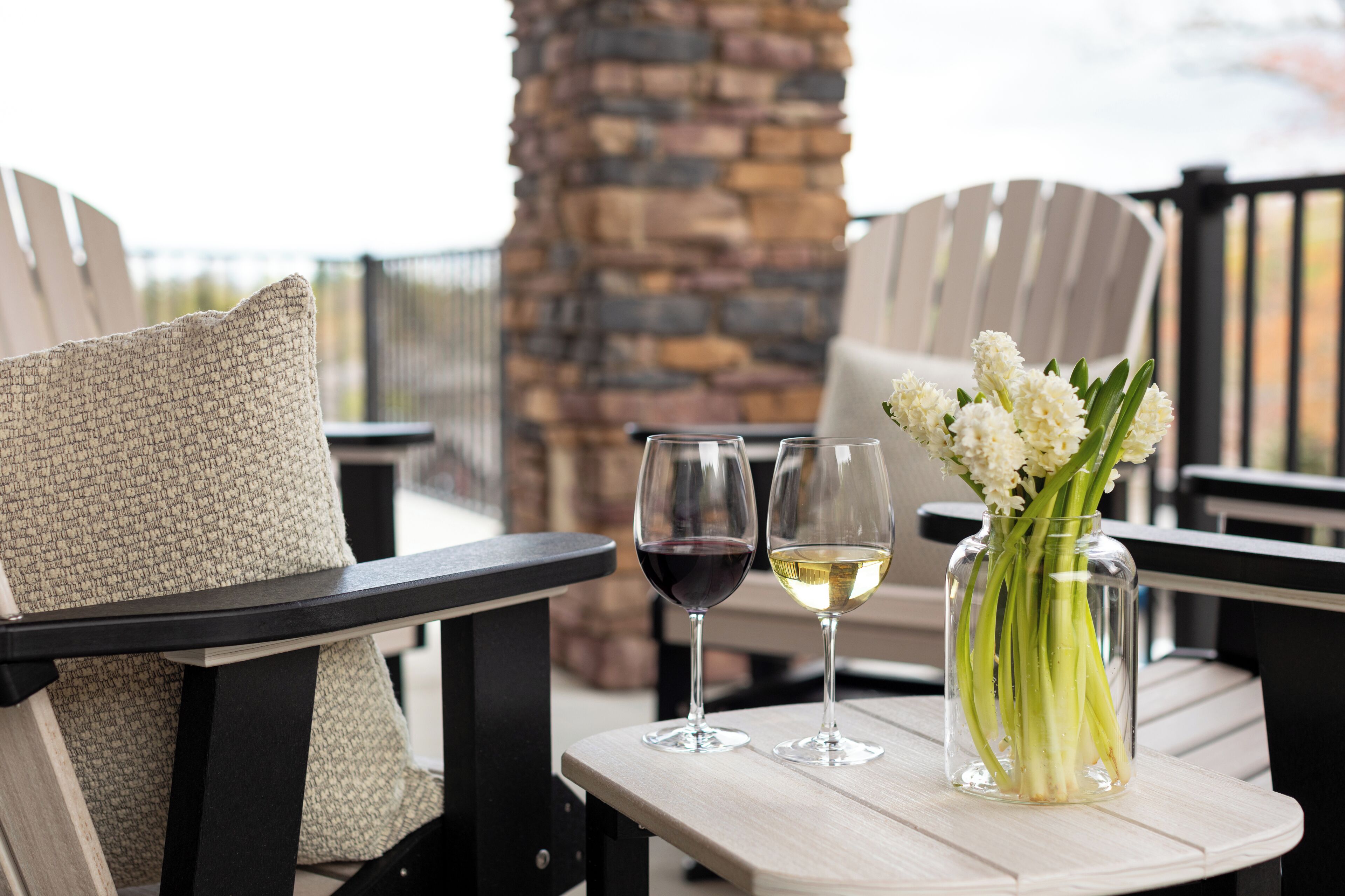 A table with two wine glasses, one with red wine and one with white wine, and a vase with white flowers.