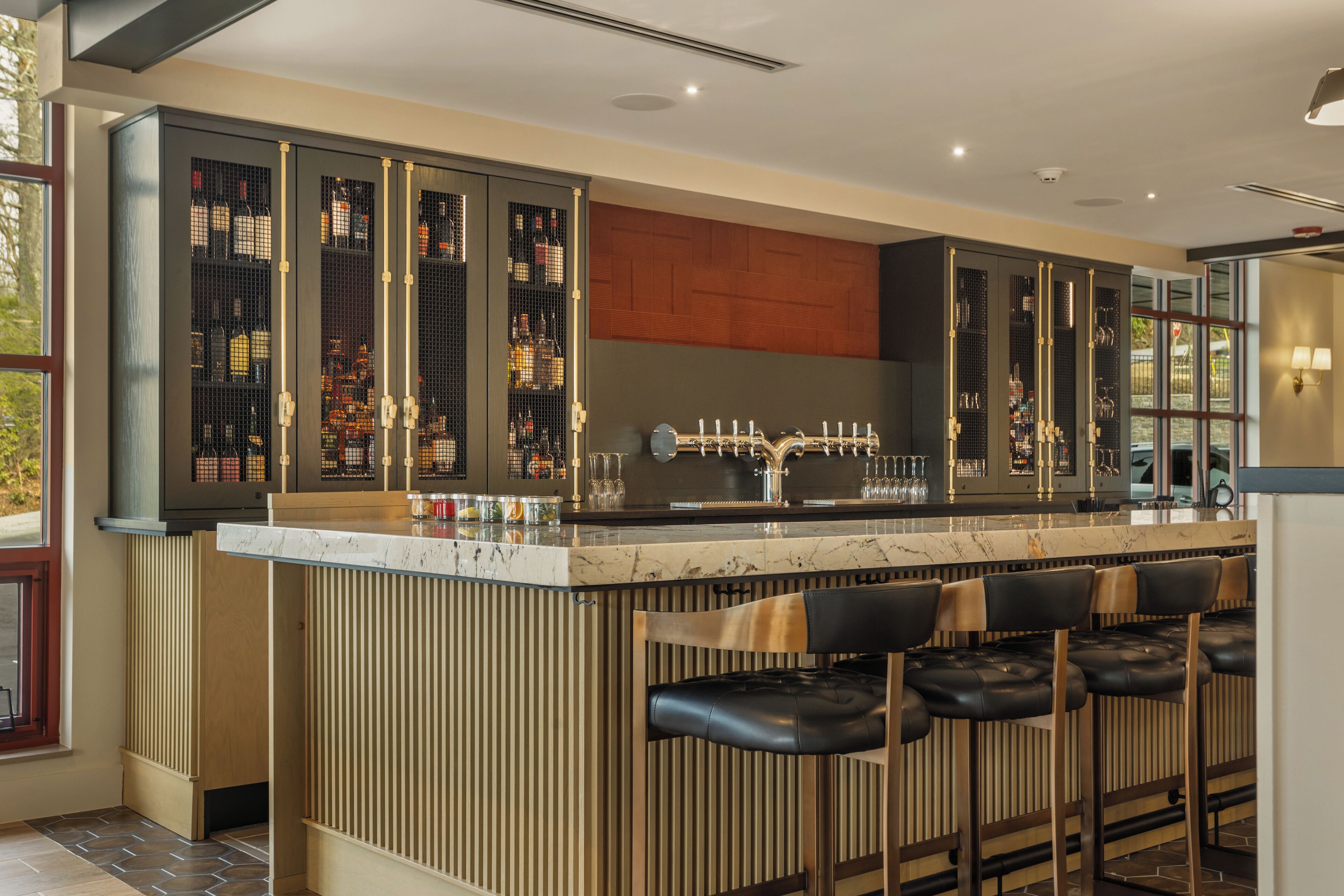 A modern bar area with a marble countertop, bar stools, and a wine rack.