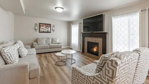 A living room with a fireplace, a sofa set, and a coffee table. - Homestead Haven | Sleeps 14 | 2 Car Garage (Clearfield)