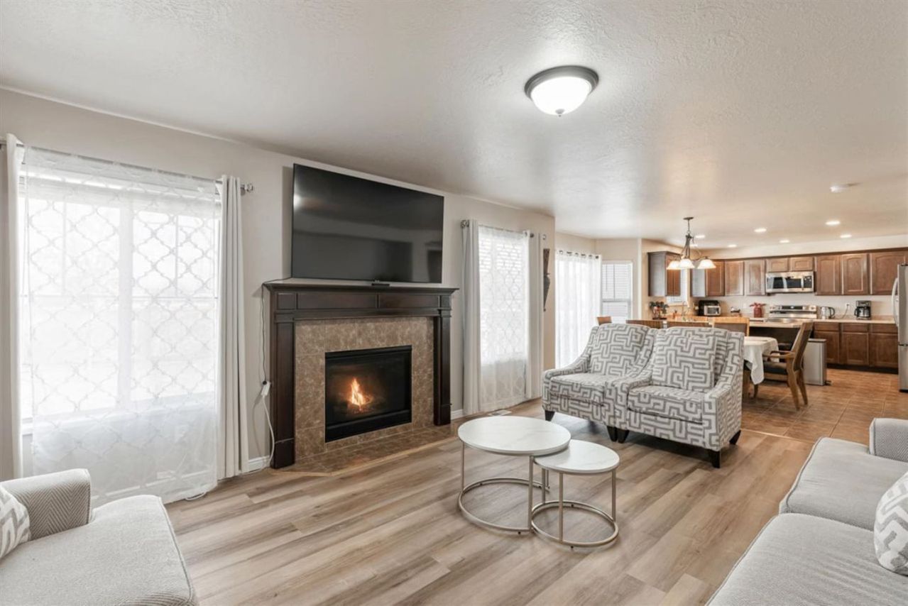 A living room with a fireplace, a sofa, two round tables, and a patterned armchair.