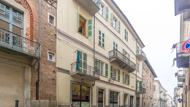 A street with buildings, a cobblestone road, and bollards.