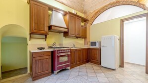 A kitchen with wooden cabinets, a red stove, a microwave, and a refrigerator.