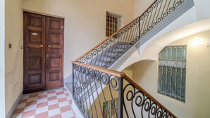 A staircase with ornate metal railings, a checkered floor, and a wooden door.