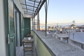 A balcony with a view of a cityscape, including buildings and a body of water.