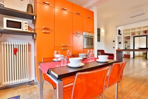 A modern kitchen with orange cabinets, a microwave, and a dining table set for four.