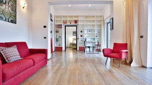 A modern living room with a red sofa, a red armchair, and a dining area with a table and chairs. - GuestHost - Terrace Concordia Amazing View (Napoli)