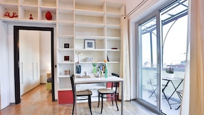 A modern room with a white desk, two chairs, a bookshelf, and a large sliding glass door to an outdoor area. - GuestHost - Terrace Concordia Amazing View (Napoli)