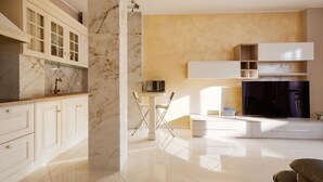 Una cocina moderna con encimeras de mármol, armarios blancos y un comedor con mesa y sillas.
