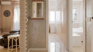 Una habitación de hotel moderna con una pared de ladrillo decorativa, un espejo grande, un reloj redondo y un piso limpio con baldosas.