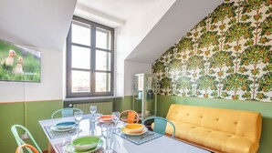 Ein Essbereich mit einem Tisch für vier Personen, Stühlen, einem gelben Sofa und einem Fenster mit Blick.