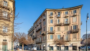 Ein mehrstöckiges Gebäude mit Balkonen, eine Kopfsteinpflasterstraße und ein klarer, blauer Himmel.