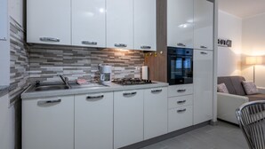 Een moderne keuken met witte kastjes, een inbouwoven en een koffiezetapparaat.
