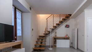 Een moderne keuken met een houten trap, een flatscreen televisie en een witte koelkast.