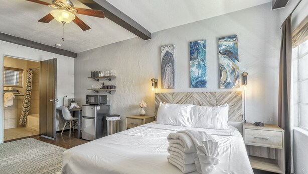 Une chambre d’hôtel équipée d’un lit, d’un bureau, d’un four à micro-ondes, d’une douche et ornée d’œuvres d’art au mur.