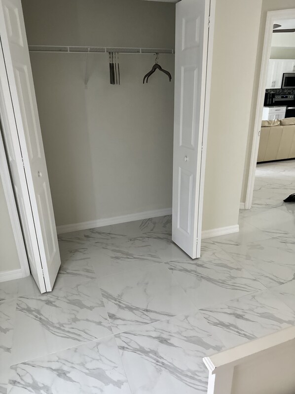 A room with a marble floor, a white door, and a coat rack against a wall.