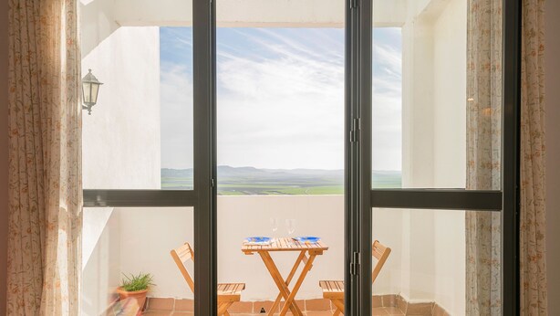 A balcony with a table and chairs, a potted plant, and a view of the landscape. - PARAISO COSTERO  - Cosy flat with shared pool (Conil de la Frontera)