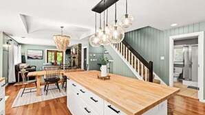 Eine moderne Küche mit einer Holztheke, Pendelleuchten und einer Treppe zu einer weiteren Ebene.