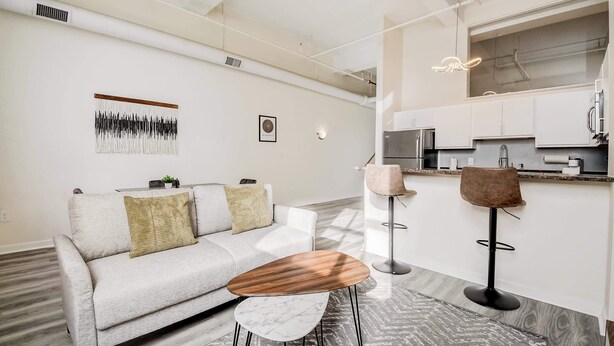 Ein modernes Wohnzimmer mit Sofa, Couchtisch und Barbereich mit Hockern.