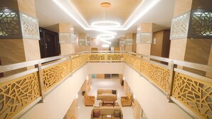 Ein geräumiger, moderner Lounge-Bereich mit einer zentralen Sitzgruppe, dekorativen Paneelen und einer zeitgemäßen Leuchte.