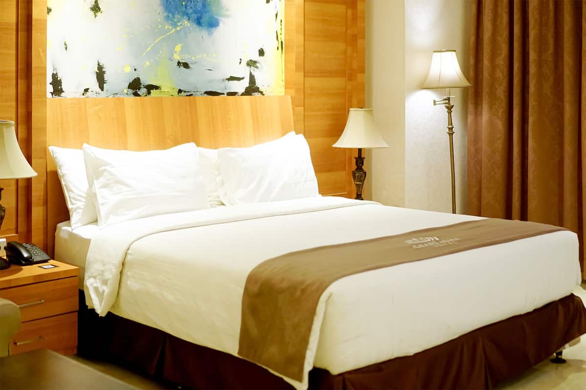 Habitación de hotel con una cama grande, dos lámparas de noche, un teléfono y un cuadro en la pared.