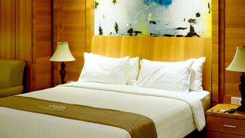 A hotel room with a bed, two bedside lamps, a nightstand, and a painting on the wall.
