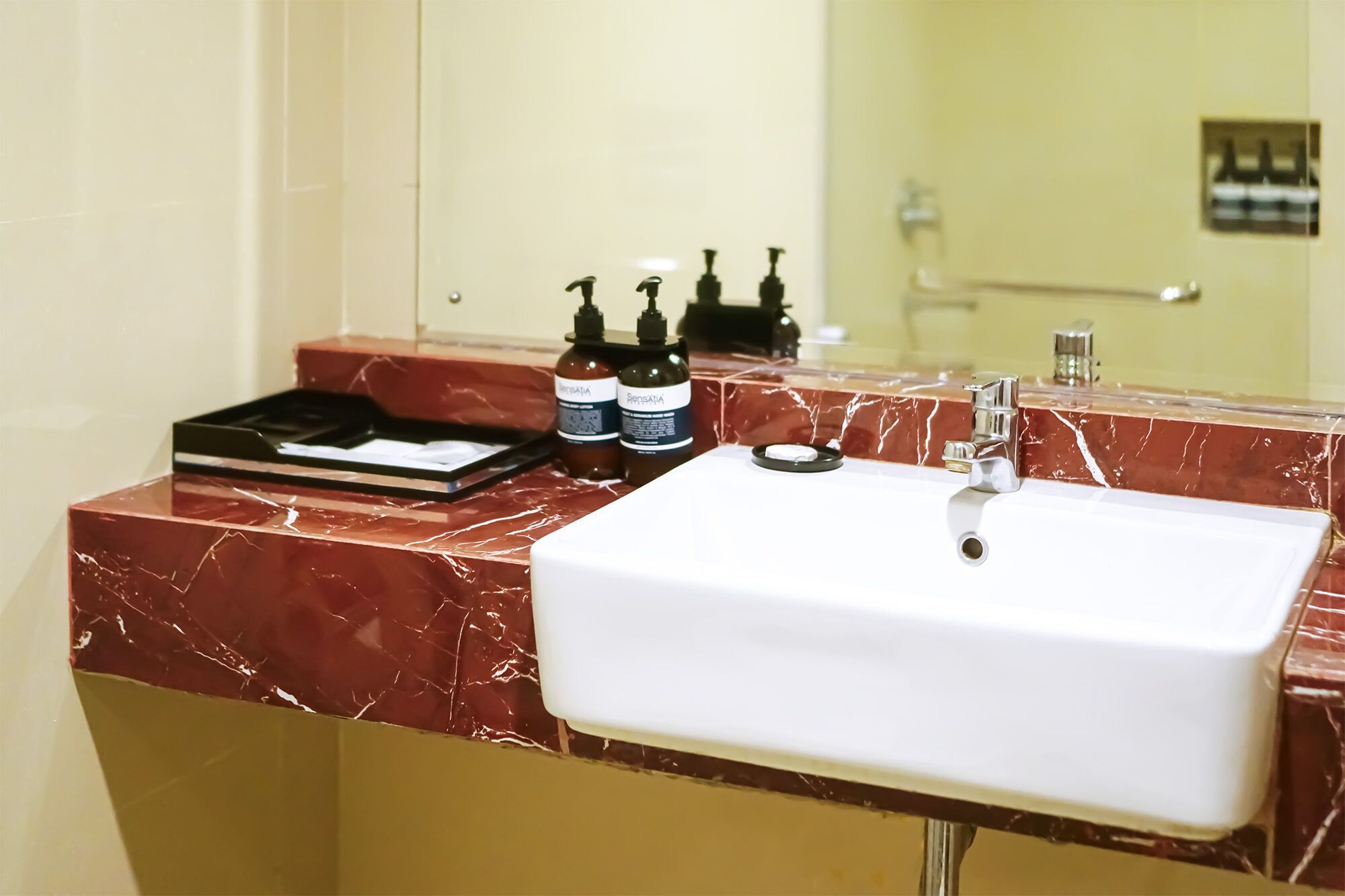 A bathroom with a white sink, a mirror, and toiletries on the counter.