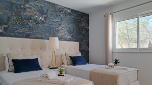 Ein Hotelzimmer mit zwei Betten, einem großen Fenster und einer blauen Wand mit Dekoration.