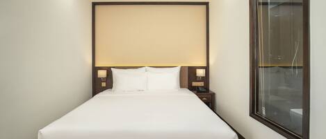 A neatly made bed with white linens in a modern hotel room.