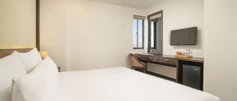 Una habitación de hotel con una cama grande, un escritorio con una silla, un televisor y una ventana.
