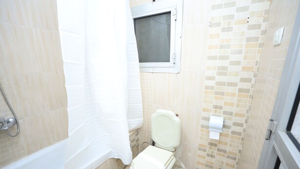 Een kleine badkamer met toilet, douche en raam.