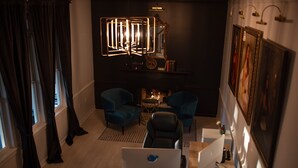 En moderne stue med et skrivebord, to blå lænestole, en pejs og et stort spejl.