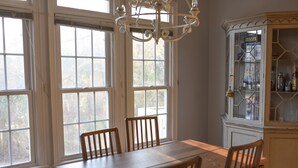 A dining room with a wooden table and chairs, large windows, and a glass-fronted cabinet. - MASTER'S TOURNAMENT RENTAL - GATED COMMUNITY - WHOLE HOUSE - 2 OWNER'S SUITES (Martinez)