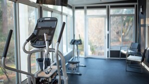 Et hjemmegym med træningsudstyr, store vinduer og en loftsvifte.