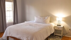 A bedroom with a bed, a nightstand with a lamp, a window with curtains, and a carpeted floor. - MASTER'S TOURNAMENT RENTAL - GATED COMMUNITY - WHOLE HOUSE - 2 OWNER'S SUITES (Martinez)