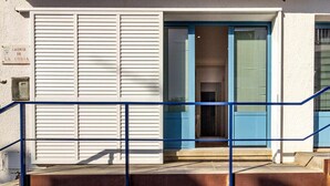 A building with a white facade, a blue door, and a blue railing in front.