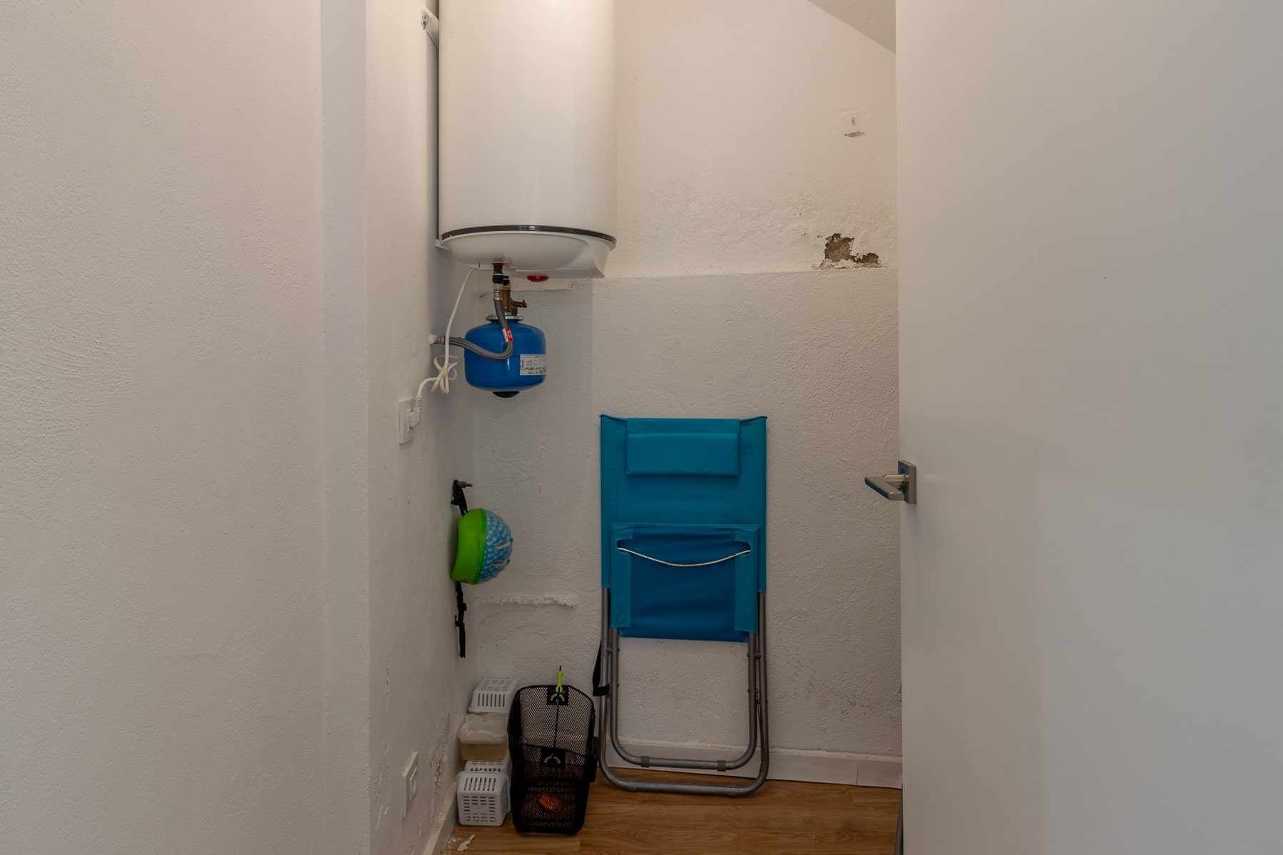 A narrow hallway with a white wall, a blue door, and a white ceiling with a light fixture.