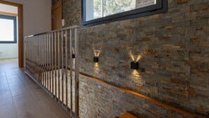 Un intérieur moderne avec un mur en pierre, une rambarde en métal et deux appliques murales.