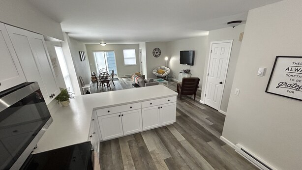 A modern kitchen with white cabinetry, a central island, and a dining area with a table and chairs. - Highland Hideaway-Newly Remodeled!  (Sheridan)
