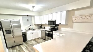 A modern kitchen with white cabinets, stainless steel appliances, and a large island. - Highland Hideaway-Newly Remodeled!  (Sheridan)