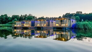 Une maison flottante dotée de plusieurs terrasses, chacune offrant un espace salon extérieur et des murs en verre.
