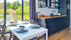 Une cuisine moderne avec une grande fenêtre, une table à manger dressée avec des assiettes et des bols, et une vue sur la verdure à l’extérieur.