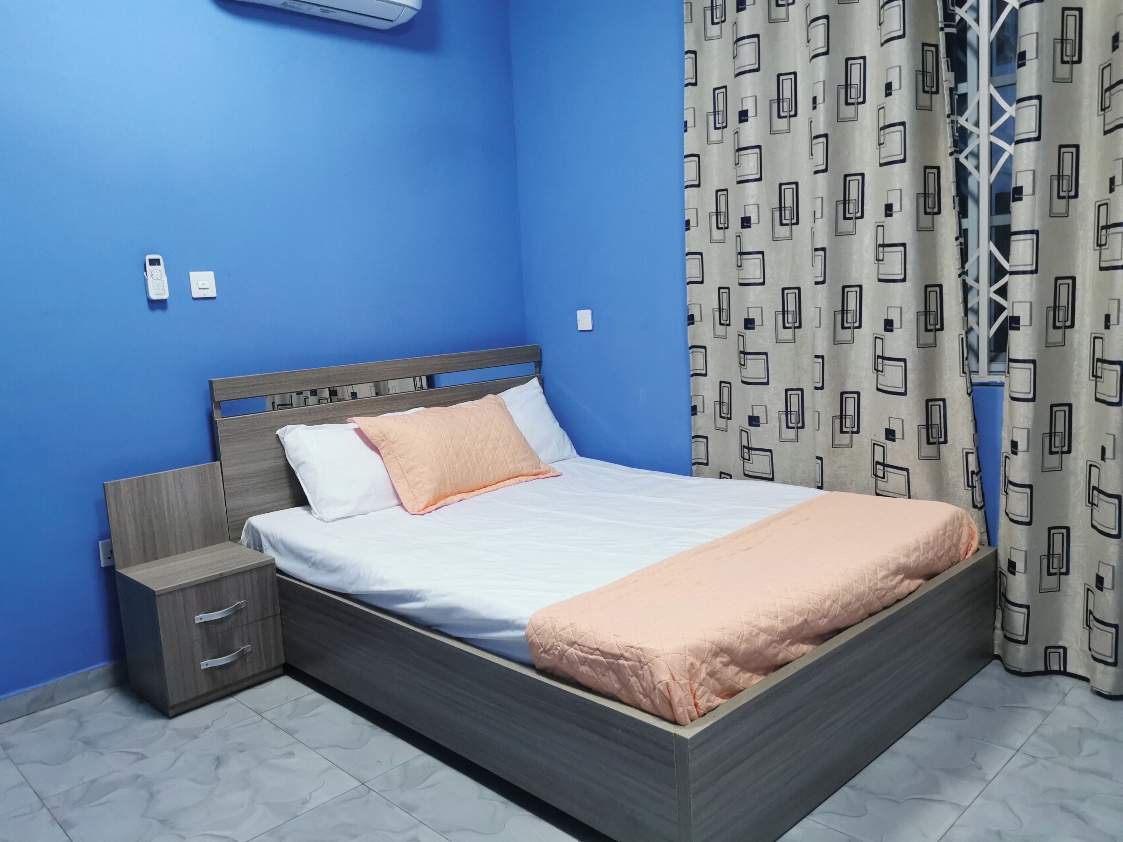 Ein Schlafzimmer mit einem Bett, einem Nachttisch, einem Kleiderschrank und einem Vorhang.