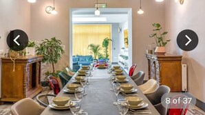 Un espace repas avec une longue table dressée pour un repas, entourée de chaises, donnant sur un salon.