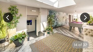 Un intérieur moderne agrémenté d’une verrière, d’une table de billard et de plantes en pot.