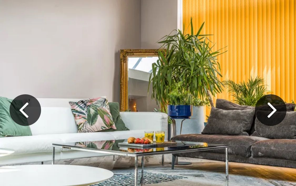 A modern living room with a white sofa, a glass coffee table, and a potted plant.