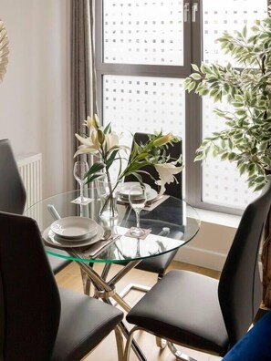 Enjoy meals in style with a glass table set for two, accompanied by a potted plant and a view of the city.