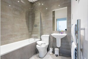 Enjoy a sleek bathroom with a wall-mounted sink, separate toilet, and glass-enclosed shower.