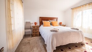 A bedroom with a wooden headboard, two pillows, a bedside table with a lamp, and a patterned rug. - SunRays  Naturist Apartment in Playas de Vera (Playas de Vera)