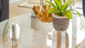Un soggiorno moderno con un tavolino in vetro, una pianta in vaso e una ciotola decorativa.