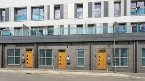 A modern building with multiple windows and doors, a flat roof, and a brick facade.